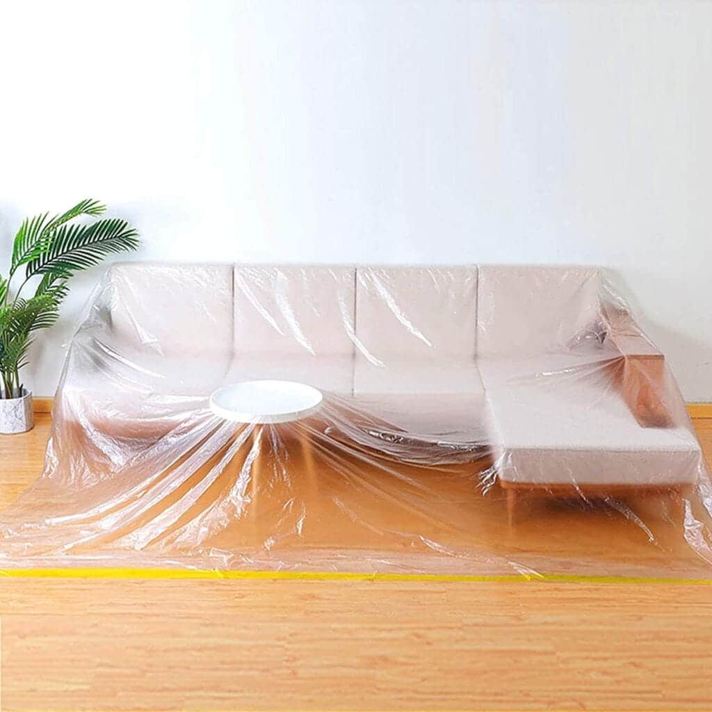 Couch and small coffee table covered with a plastic sheet.