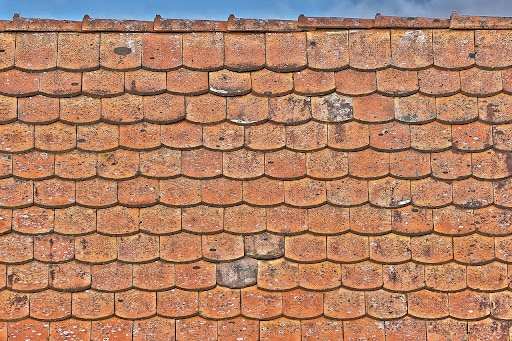 Old terracotta roof tiles showing wear, with visible moss and weathering.