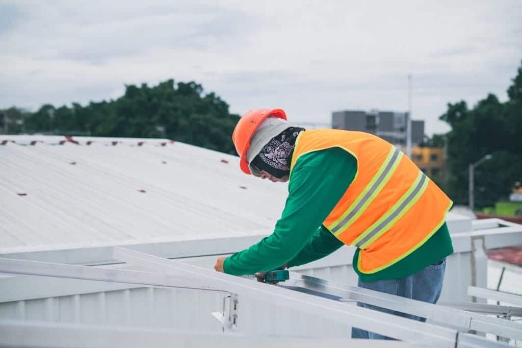 A worker in safety gear inspecting and working on a commercial roof