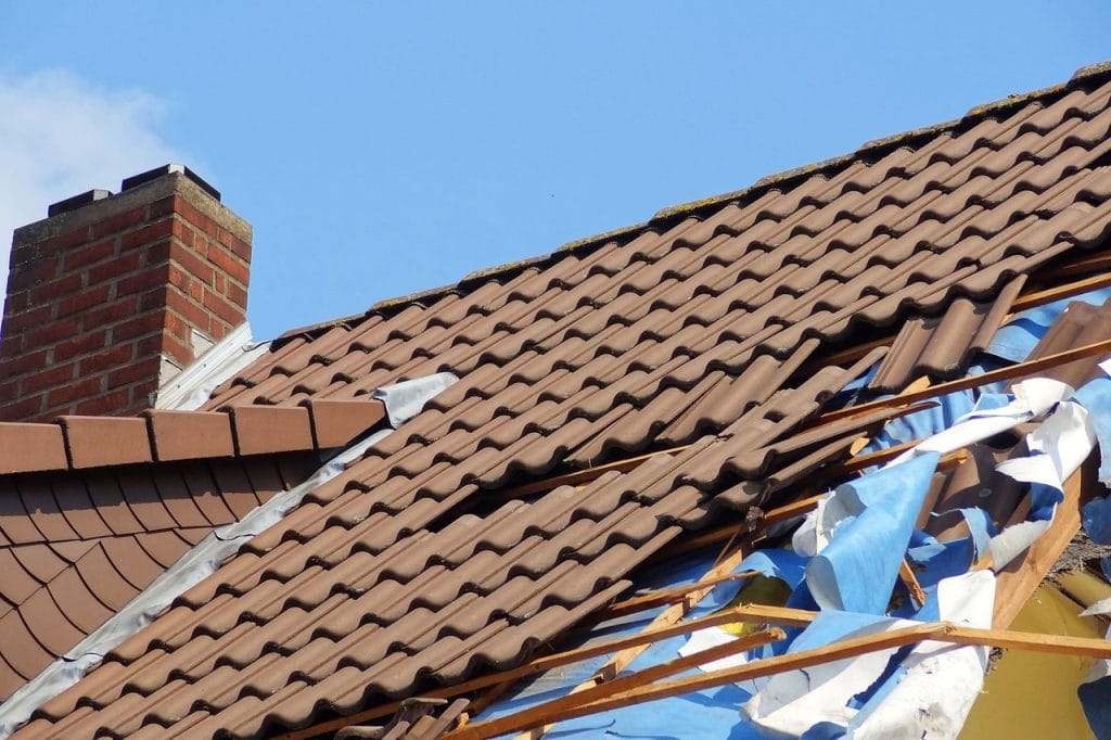 Roof with damaged tiles and exposed underlayment.