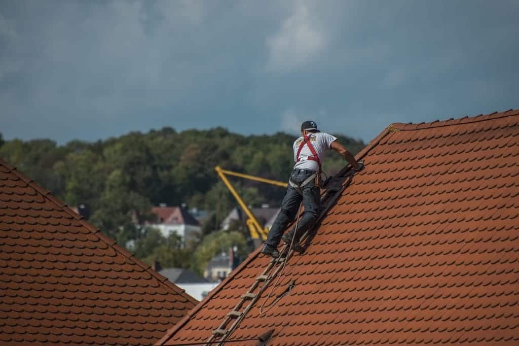 Roof repair worker climbing a ladder to fix a roof